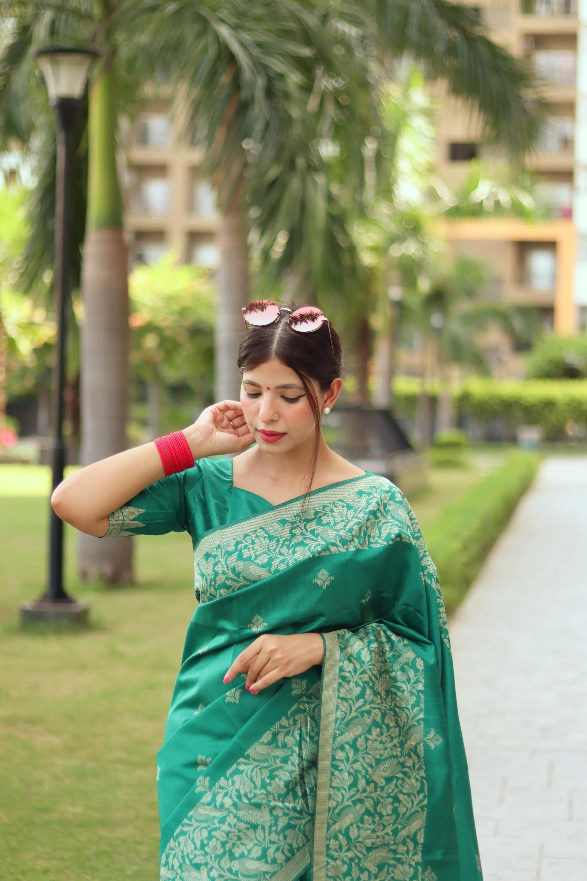 Woman wearing tropical green traditional weaving saree posing gracefully in a lush outdoor setting